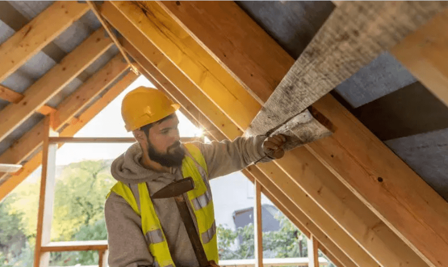 Insulation contractor checking attic roof insulation with a hard hat
