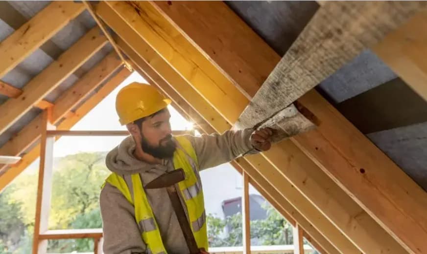 Insulation contractor checking attic roof insulation with a hard hat