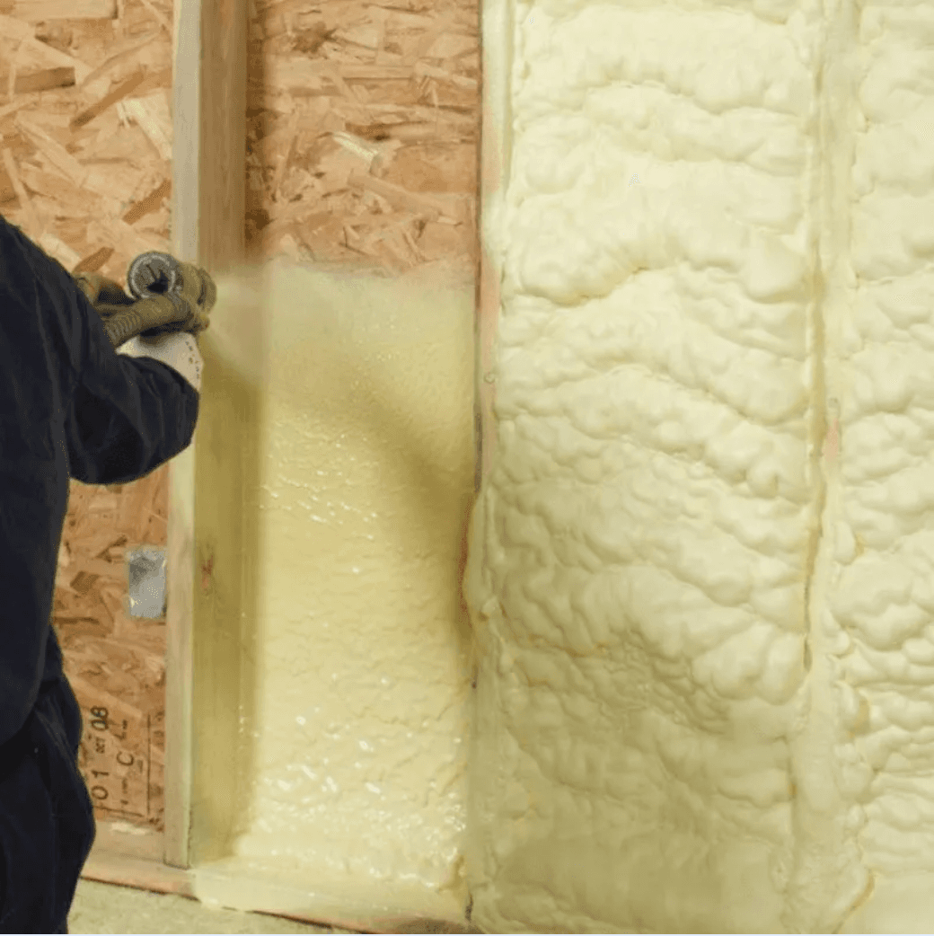 Closed-cell spray foam being applied inside a framed wall cavity