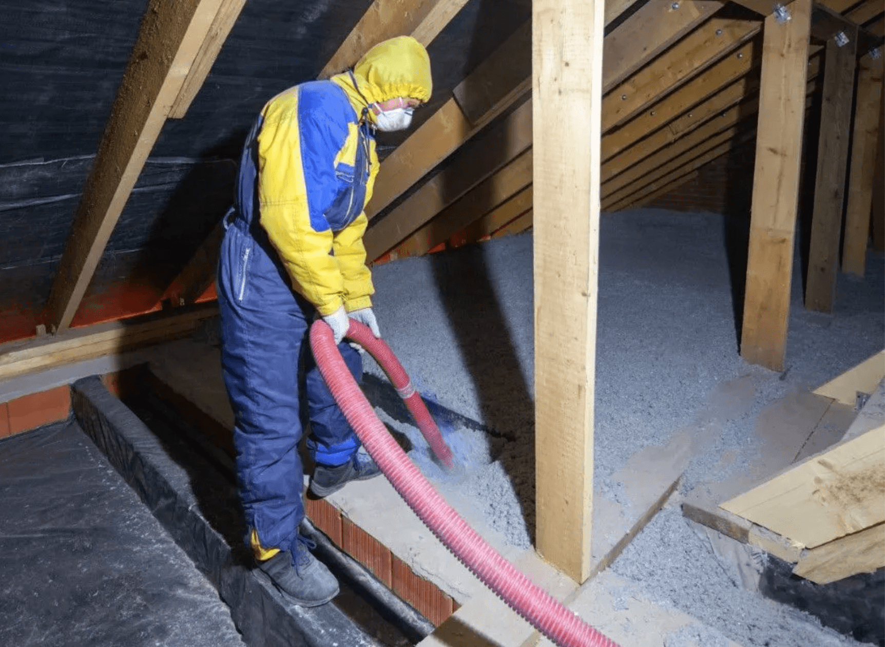 Technician blowing loose fill attic insulation between roof framing