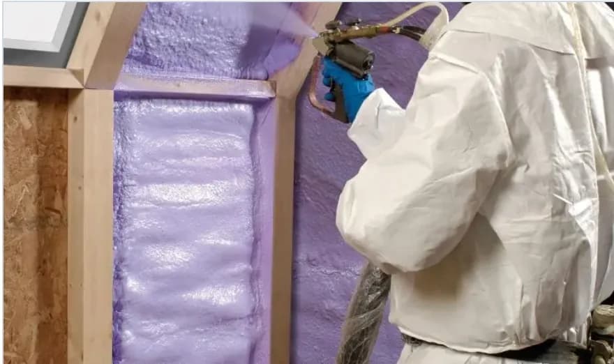 Purple closed-cell spray foam being applied along a roofline